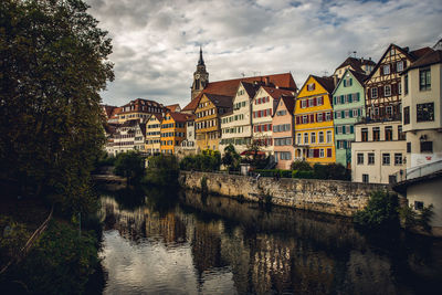 Buildings by river in town against sky