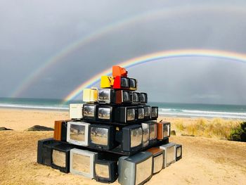 Stack of television set at beach against sky