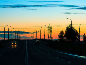 Cars on street against sky during sunset