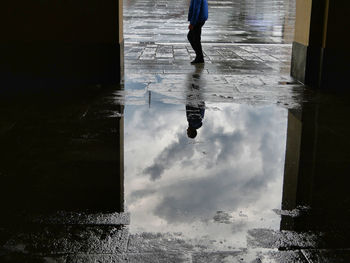 Low section of man walking on wet street