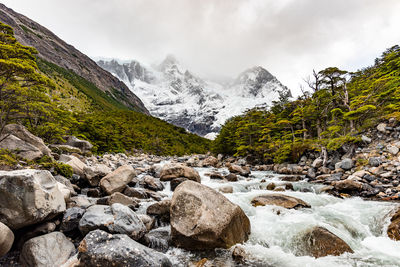 Scenic view of stream amidst rocks against sky