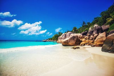 Rock formations on beach against blue sky