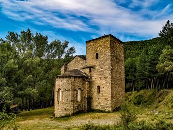 Old ruin amidst trees and buildings against sky