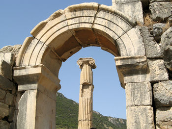 Ruins of roman column framed by arch.