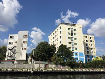 Low angle view of buildings by river against sky