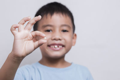 Fingers kid holding torn out baby milk tooth with little blurred boy face looking at tooth 