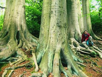 Woman sitting on large tree roots in forest
