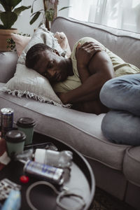 Worried man contemplating while lying on sofa