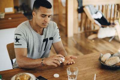 Man taking pills while having breakfast at table