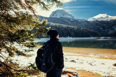 Rear view of man standing on mountain against sky