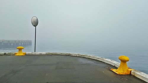 Yellow bollards by sea against sky