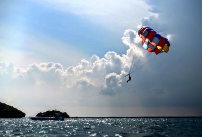 Low angle view of paragliding over sea against sky