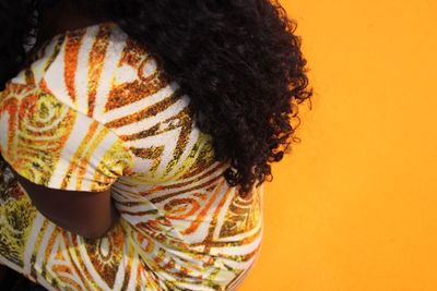 High angle view of woman sitting against yellow background