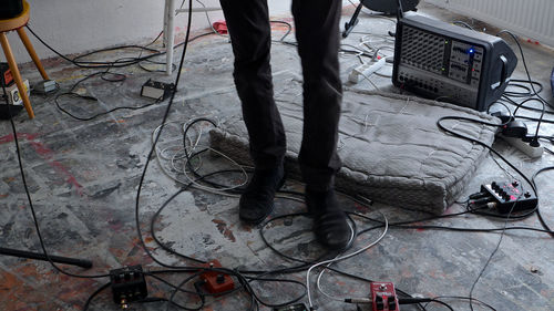 Low section of man standing amidst cables