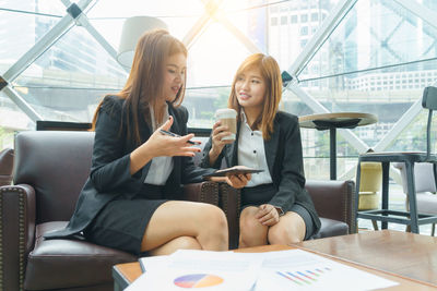 Young woman using mobile phone while sitting in laptop