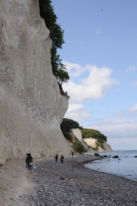 People on rock by sea against sky