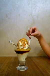 Hand holding ice cream on table