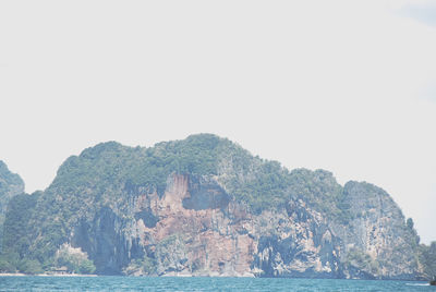 Rock formations by sea against clear sky