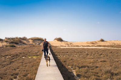 Rear view of man walking on country road