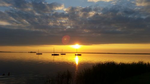 Silhouette of boats in lake against cloudy sky at dusk