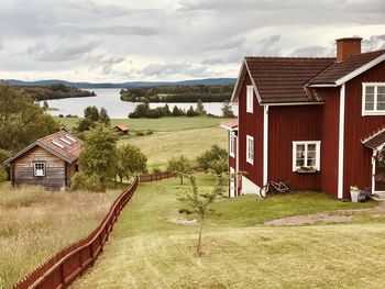 House on field by houses against sky