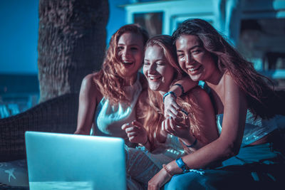 Happy friends using laptop on table