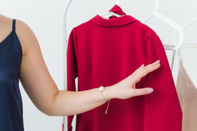 Midsection of woman holding red standing against wall