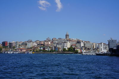 Sea by buildings against blue sky