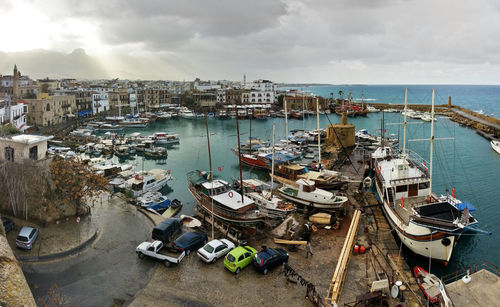 Boats in harbor against cloudy sky