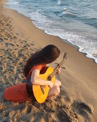 High angle view of a woman playing guitar on the beach