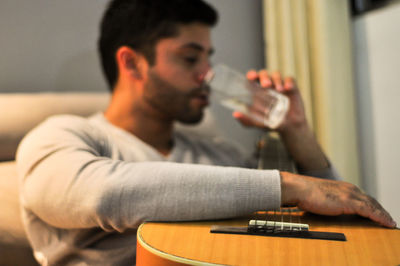 Midsection of man holding beer while sitting on table