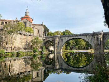 Arch bridge over river against buildings