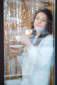 Woman drinking coffee in cafe or at home in winter. dreamy relaxed adult female in her 40s. view