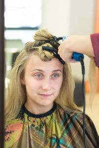 Cropped hand of person styling woman hair