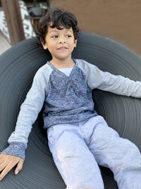 High angle view of boy looking away while sitting on chair