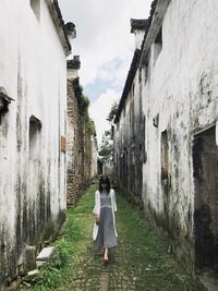 Rear view of man walking on road amidst buildings