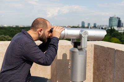 Side view of man looking through binoculars