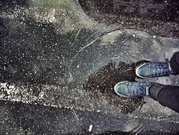 Low section of person standing on puddle during monsoon