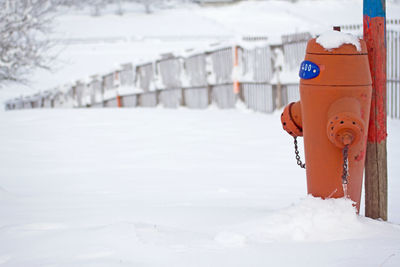 Red fire hydrant in front of now covered field during winter