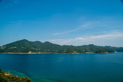 Scenic view of sea and mountains against blue sky