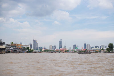 Modern cityscape by sea against sky