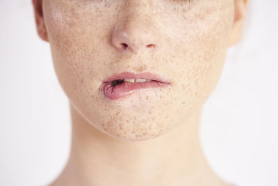 Midsection of woman with freckles on face against white background