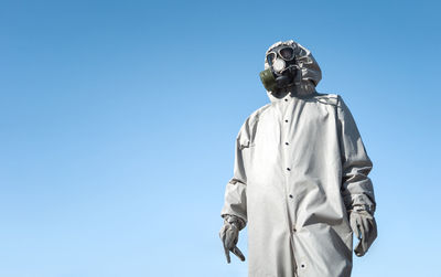 A man in a gas mask and a protective suit. blue sky in the background. with copyspace.