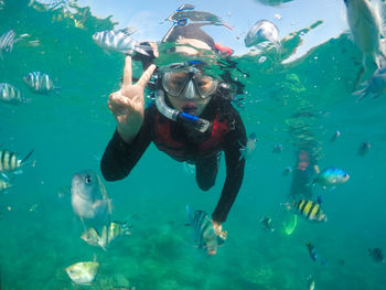 Portrait of young woman gesturing while snorkeling in sea