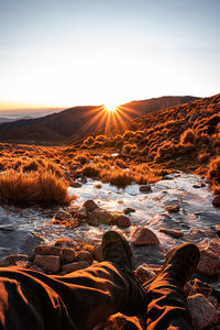 Low section of man on beach against sky during sunset