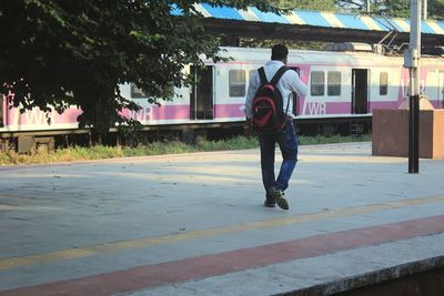 Rear view of man skateboarding on road in city