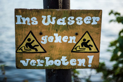 Close-up of warning sign against sky