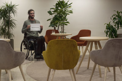 Man holding paper with text while sitting on wheelchair