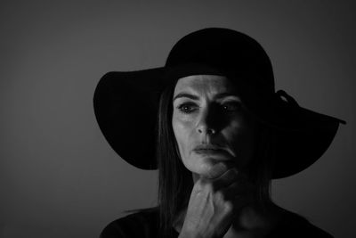 Close-up of woman wearing hat against gray background