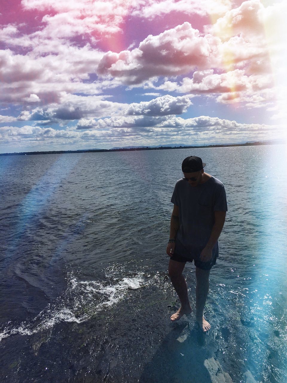 REAR VIEW OF MAN STANDING ON SHORE